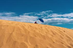 man with umbrella on a sand dune