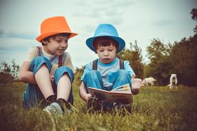 two boys reading a book in nature