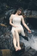 young sexy asian girl sits on rock at water