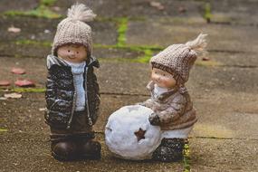 Figures of children in clothing making snowball