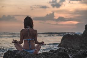 girl in a swimsuit meditates on the seashore