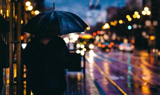 man under an umbrella on a city street in bokeh background