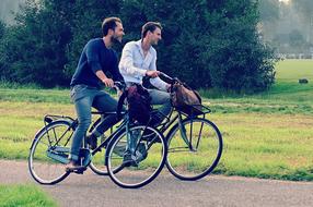 men ride bicycles on the road