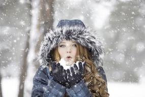 girl is blowing in the snow in her arms