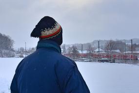 man looking at a train in winter