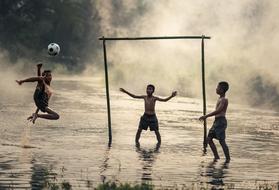boys are playing football in the water in Cambodia