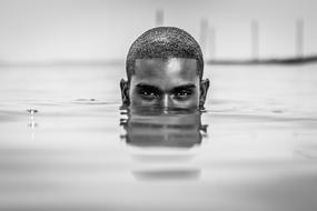 monochrome photo of the head of a man sticking out of the water