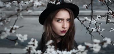 portrait of a girl in a black hat among white flowers