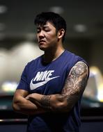 Asian man with tattoos and in blue and white "Nike" t-shirt