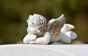 photo of a statue of a stone lying angel on a tombstone