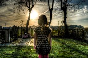 photo of a girl in the backyard of the house against the evening sky