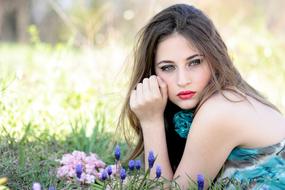 Portrait of the beautiful girl in make-up and colorful dress, on the beautiful meadow with the colorful grass and flowers, in sunlight
