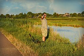 man standing on the grass and fishing