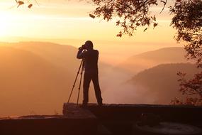 silhouette of Photographer with Camera on tripod at scenic landscape