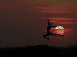 silhouette of a jumping girl at sunset