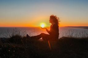 girl holding sunset in her hands