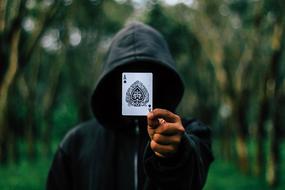 photo of a man in a hood with an ace of spades card