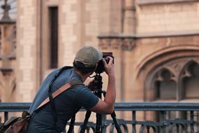 Photographer, man with Camera in front of historical building