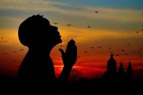 silhouette of man Praying at sunset sky
