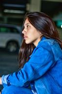 Profile portrait of the girl, in blue clothing, near the cars