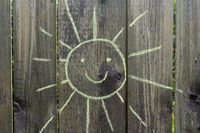 smiling Sun, chalk drawing on wooden fence