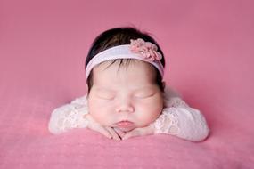 Newborn asian Baby girl sleeps at pink background