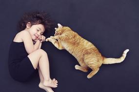 photo of lying young girl and ginger cat