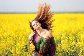 young girl with long hair among a bright yellow field