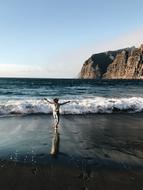 Person, on the beautiful ocean beach with waves and mountains