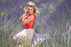 Smiling, beautiful, blonde girl in red and white dress, on the beautiful, violet lavender field
