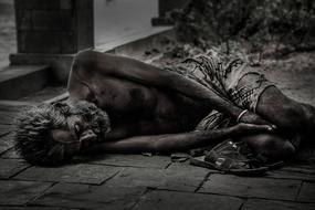 black and white photo of a homeless man is lying on the street