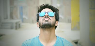 Portrait of the bearded man, with the colorful, shiny glasses, at blurred background