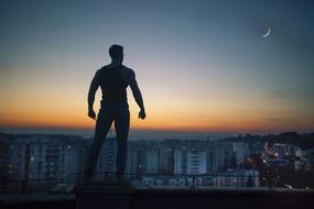 silhouette of a man on the roof against the background of a night city