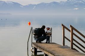 father and son on a wooden pier by the lake