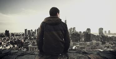 young man sits on the roof of a tall building