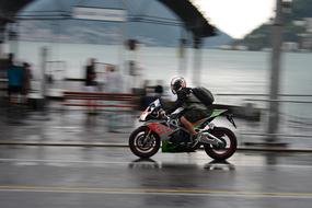 motorcyclist is driving fast on wet road