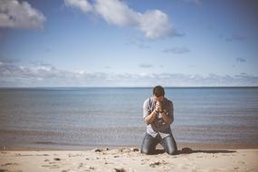 man in prayer on the beach