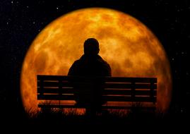 silhouette of a man on a bench against the background of a large yellow moon