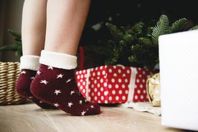 Christmas Celebration, female legs at gift boxes and fir tree