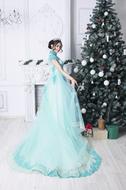 young girl in long green dress posing at Christmas Tree