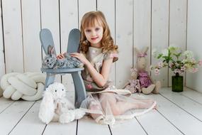 a girl in a beautiful dress stroking a rabbit in a photo studio