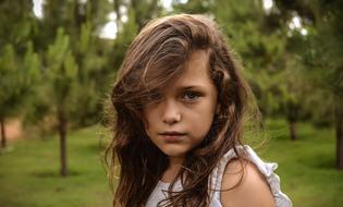 portrait of an innocent girl against a background of green trees