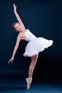 Beautiful ballerina in white dress, dancing at blue background