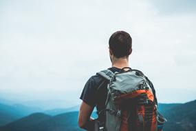 tourist with a backpack on the top of the mountain, back view