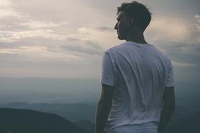 Back view of the standing man, looking on the beautiful mountains in fog