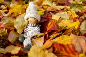 Cute and beautiful girl doll figure, among the colorful leaves, in autumn