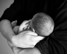 person holds newborn baby on his arms