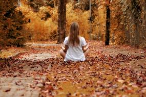 caucasian Girl meditating in park at fall
