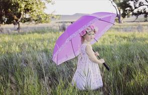 girl with a floral wreath and a purple umbrella in the country