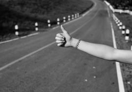 female hand thumb up at road